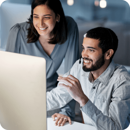 Two people smiling whilst looking at a computer screen of estate planning software